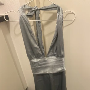 Klänning från Cider - Klänning i satin från Cider med öppen rygg med knytning i nacken. Nyköpt. Tendens att bli skrynklig, men hur fin som helst när man strukit den!