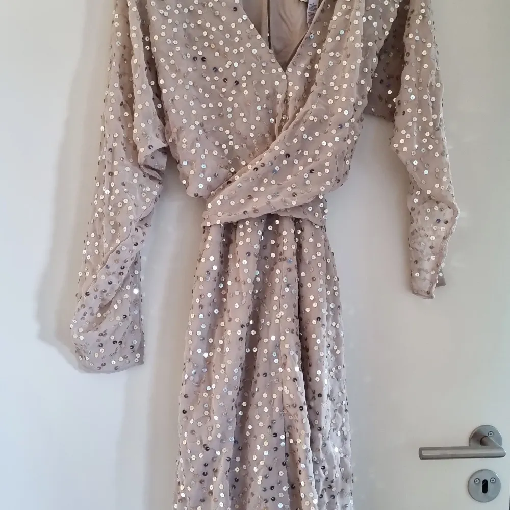 Superfin beige klänning med paljetter och slits. Ny med etikett. Nypris hos asos: 1209kr Har den i två storlekar, 42 och 44.. Mekot.