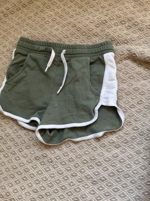 Gröna mjukis shorts - Ett par militär gröna mjukis shorts köpta på HM för 80kr. Är i fint skick och är bra nu i sommar eller för att använda som pyjamas.