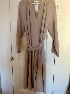 Snygg klänning från HM Trend. Helt ny.  - Passar allt från S-L. Stretch. Skärp i midjan. 