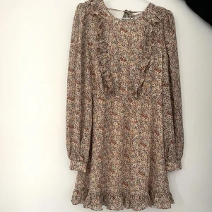 Blommig klänning  - Söt blommig klänning med volanger och öppen rygg! Har också söta detaljer som man ser på tredje bilden! 