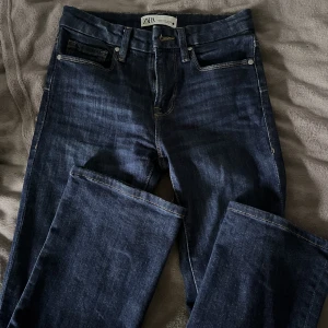 Mörkblå Bootcut Jeans - Säljer mina trendiga lågmidjade bootcut jeans från zara! Dom var tyvärr för små för mig, nästan aldrig använda, stl 34💕