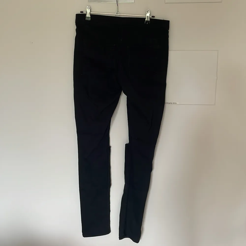 Ett par svarta jeans med mycket stretch. Hål vid knäna. Stretchig midja istället för gylf och knapp. Jeans & Byxor.