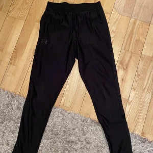 Under armour träningsbyxor  - Under armour träningsbyxor i strl M, fint skick. Sparsamt använda. Dragkedja vid fickorna och snören vid insidan av midjan.  Herr byxor.