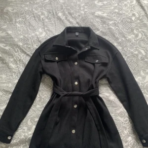 Kappa  - Svart kappa, med knappar. Använd Max 5 gånger. 