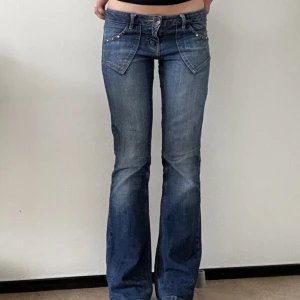 Lågmidjade jeans med unika detaljer - Säljer nu dessa dödligt snygga lågmidjade jeans då de inte kommer till användning. De är second hand och på lappen står det storlek 8, men passar mig perfekt som bär storlek S och XS. 💕🤩 DM för mått och fler bilder!