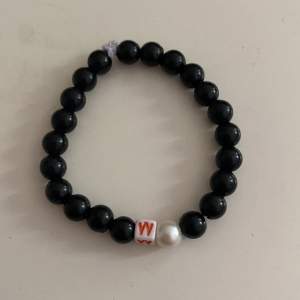 Ett handgjort armband med ändlös svarta pärlor med en vid pärla och en bokstav i mitten❤️