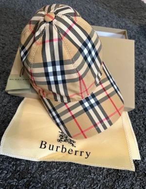 Burberry keps  - Burberry keps storlek M. kepsen kommer med alla tillbehö, aldrig använd lappar sitter fortfarande kvar. Eller byte,
