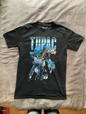 Vintage t-shirt Tupac - Vintage T-shirt med tupac tryck i storlek M herr. Den är i bra skick. Längd: 76cm  Bredd: 51cm  Ärmlängd: 21cm  Kan fraktas eller mötas upp i Malmö/Lund.