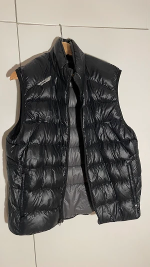 RLX dunväst - Svart Ralph Lauren (RLX) dunväst med en liten reva fram. Snygg glansig färg