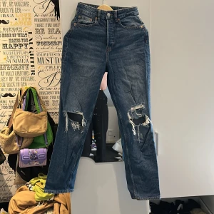 Blåa jeans  - Blåa jeans med hål vid knäna från HM i storlek S. De är medel tjocka och långa.