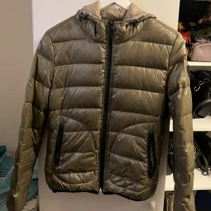 Dunjacka  - En olivgrön dunjacka, använd en vinter. Passar junior eller som en xs. 