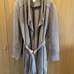 Cool långrock - Ofodrad långrock/kofta? Utåtvända sömmar och fickor. Kamelbeige i färgen.  Märke Pearl. Strl L. Bystmått: 56 längd: 109