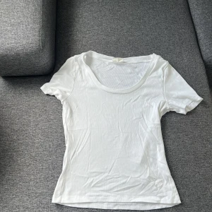 Vit kortärmad ribbad topp - Vit kortärmad ribbad topp från ginstricot. Helt ny och aldrig använd så i perfekt nyskick. Hade även passat L