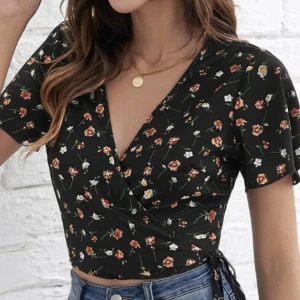 Svart, blommig, wrap-around topp - En svart, fin, blommig warp-around. 