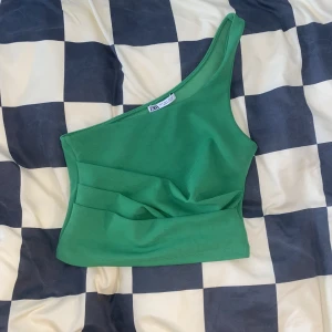 Grön one shoulder - Grön one shoulder topp från Zara! Den har lite sånna där fina veck på framsidan! Aldrig använd!
