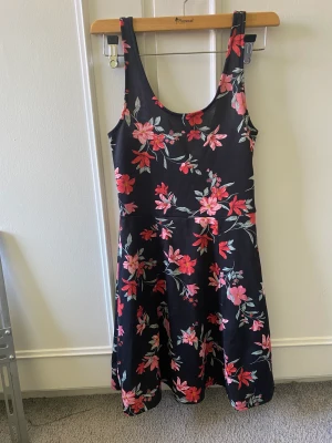 Blommig klänning - En svart klänning med blommor på, den har knappt används.