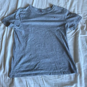 T-shirt - Tjena, ja säljer en clean grå Tommy Hilfiger t-shirt. Köpt för 250 säljs för 100 Jag säljer den pga den är för liten för mig. Storlek 12-14 år. Ja står självklart för frakten, kontakta mig via frågor eller fler bilder!