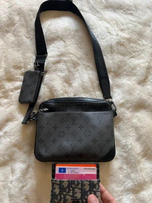 Louis vuitton väska - Hej, säljer nu min Louis Vuitton trio Messenger bag. Köpt av Eliott malhotra som ni kan se i det inringade området på kvittot. Har inte kvittot själv för han ville inte skicka med det av någon anledning! Har även box också! Nypris 26000