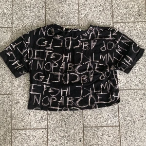 Tshirt - Croppad T-shirt med bokstäver på. Ganska bra skick, köpt second hand men jag har aldrig använt den. 