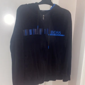 Boss huvtröja - Tja, säljer denna boss koftan då den är för liten för mig och inte min stil längre, den ä väl använd så det finns ett litet hål på höger baksida arm och ett vid fickan på magen (se bilder), priset är inte hugget i sten.