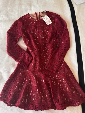 Zara klänning NY vinröd spets  - Snygg klänning från zara. Helt ny med prislappar kvar. Slutsåld . Perfekt till hösten eller julens vinröd spets med beige underkjol. Volanger nedtill. Vackert fall. Storlek medium 