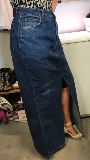 Lång jeanskjol  - Snygg jeanskjol med slits bak och fram. Mörkblå. Omsydda av jesnsbyxor. Midjemått ca 90cm och hel längd är ca 112 cm 