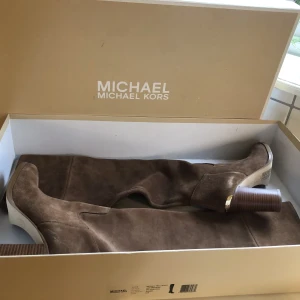 MICHAEL KORS Regina Tall Dk Caramel Suede Knee High Boots Size EU 39   - Aldrig använda, endast provat inomhus. Jag har vanligtvis storlek 38, men fick gå upp en storlek i dessa.  Bruna i mocka med gulddetalj.