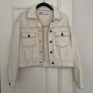 SOMMARJACKA (ZARA) - Jättefin somrig beige lite croppad jacka med bruna knappar från Zara. Jeansliknande material. Bra/ok skick, har några fläckar på vänster framsida (se bild 3) och på ena ärmen 