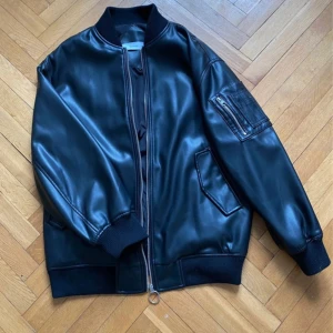 Bomberjacka i skinn  - En svart bomberjacka i fake skinn ifrån bershka i storlek M/L. Den har ett litet tryck på ryggen men som inte syns jättemycket (se bild 2 vs bild 3). Köpt begagnad men aldrig använd av mig och skulle bedöma den i ett gott skick, näst intill nyskick💕