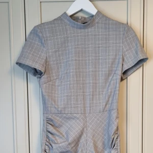 Elegant basic klänning - Elegant basic klänning i grårutigt mönster. Tight modell så passar även dig med storlek 34