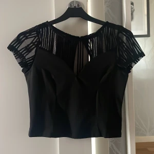 Croppad topp - Använd 1 gång med ett par högmidjade kostymbyxor för en festlook men ändå classy. Mesh tyg upptill som på bild, sömmar framtill för att framhäva ens former på ett fint sätt, knapp i nacken (bild 3h)