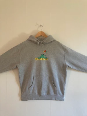 Butter hoodie - Denna hoodie är från Butter och har ett tryck på framsidan med en groda och loggan. Den har typ tre minimala röda färgprickar på fickan som man ser på tredje bilden. Förutom det är den i fantastiskt skick. Pris kan variera. 