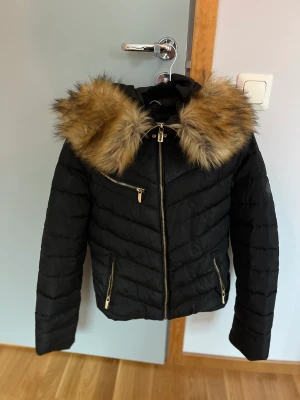 Svart vinterjacka från Roco Baroco - Svart vinerjacka med fejkpäls från Roco Baroco. Använd en vinter så den är i bra skick. Den är väldigt varm så det är den perfekta vinterjackan speciellt om man fryser.