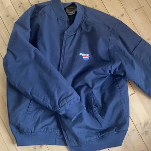 Vintage jacka  - Snygg baggy jacka jag köpte i våras på beyond retro. Har 2 fickor plus 1 på ena armen. Köpte för 500 och säljer för 300, använd 2-3 ggr. Riktigt skön och baggy, vintage oxå :) Den är blå/mörkblå med en pepsi logga fram.