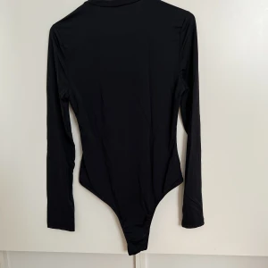 Svart body ny large - Oanvänd, storlek large. Materialet är lite tunnare glatt material.