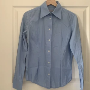 Ljusblå skjorta från Tiger - Skjorta från Tiger of Sweden i ljusblå färg. Lätt färgskiftning i armhåla enligt bild. Figursydd.