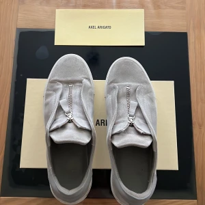 Axel Arigato skor  - Ett par fräscha gråa skor som knappt är använda, dom är i riktigt bra skick och är äkta. Köpte dom för 2500 och säljer dom för cirka 800, storleken är 46,5 