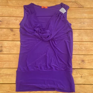 Topp - Lila draperad topp  Minns ej vart den är köpt  Står inte vilken storlek den är i men den är väldigt stretchig så skulle gissa på att den passar S-M
