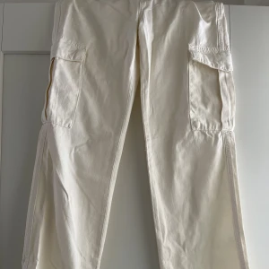 Cargobyxor - Benvita lågmidjade cargobyxor. Sitter jättebra och bra längd. Säljer pga har två likadana så dessa är aldrig använda.