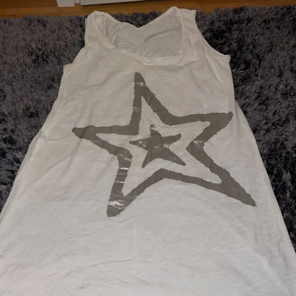Vit lång tröja med en silver stjärna har haft på mig den ett par gånger ser ut som ny. . T-shirts.