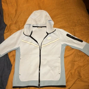 Nike Tech ljusblå - Jag vill sälja min Nike tech pågrund av att jag inte använder den. Den har små fläckar som knappt syns, skick 8/10 och använt sällan.