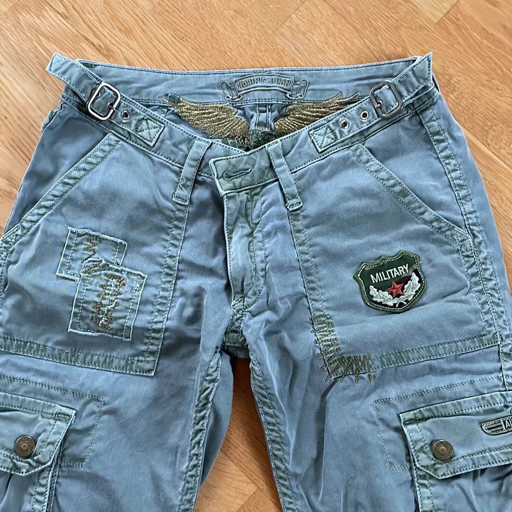 Supersnygga lågmidjade cargobyxor med gulddetalj från Robin’s jean.  Köpta secondhand men aldrig använda av mig. Skriv för fler bilder! . Jeans & Byxor.