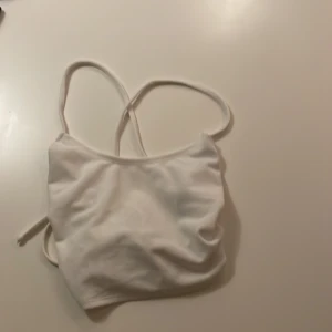 Tröja - En vit tunn topp som är öppen i ryggen. Den är använd en gång och därför säljer jag den nu. Den är alltså i fint skick. Storlek XS