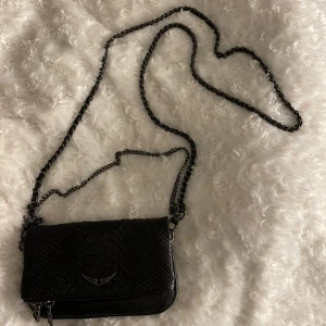 Väska  - Liten svart Zadig väska med lite orm mönster. Använd men i fint skick. Vet inte om den är äkta eller inte då jag inte har nåt kvitto eller dustbag