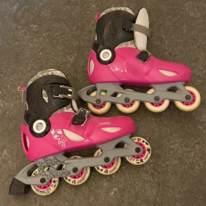 Rullskridskor  - Rosa och svarta rullskridskor. De har använts få gånger då jag växte ur dem snabbt. De är i bra skick, utöver få skråmor (se bild 3) och även att den ena bromsen saknas på en av dem (se bild 1, den bakre) Kontakta vid frågor!