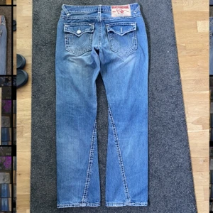 True religion Joey Super T - Midjemått: 34 🎃🎃ytterben: 107cm 🎃innerben: 80cm🎃midja rakt över: 43cm 🎃benöppning: 20cm 🎃🎃saknar knapp på höger bakficka, fläck på framsidan av högra benet.