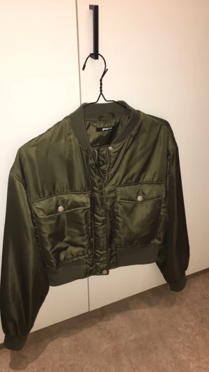 Bomberjacka satin  - Gina tricot i storlek Large  Kort modell med stora fickor i grön satin. I fint skick! 