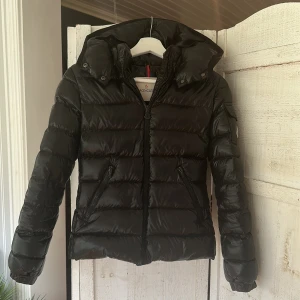 Moncler Bady Jacka - Så snygg jacka från Moncler. Barnstorlek 12Y/152, passar ca XXS/XS. Vintage!! Finns lite slitningar på dragkedjorna och cartoonlappen har jag fått sy fast extra på ett ställe. Inget som märks när man bär den.  Fixar gärna fler bilder vid intresse!!