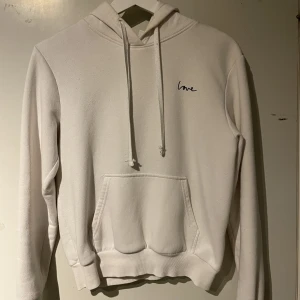 Vit hoodie med liten text - Vit skön hoodie. Säljer då den inte kommit till användning av mig så mycket. Liten fläck vid ena armbågen (kan ses på 3e bilden). Texten står det ”love” på. Från H&M. Storlek XS. Säljer billigt då jag inte vet om fläcken går att få bort. 